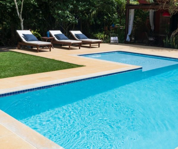 Outdoor pool in garden with empty sun loungers in luxury resort and blue water